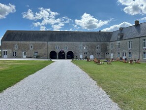 A large stone building with a gravel driveway leading to a set of arches. - Château de Franquetot  (Sainte-Mère-Église)