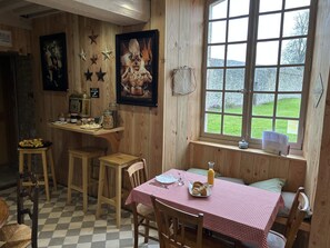 Une cuisine chaleureuse aux murs en bois, avec une nappe à carreaux et une fenêtre donnant sur un paysage verdoyant.