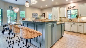 A spacious kitchen with a large island, bar stools, and pendant lighting. - Charming 4-bedroom Lake house in Bonham with Pickleball/ Basketball court. (Bonham)