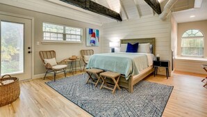 A bedroom with a large bed, a small table, two chairs, a rug, and a window. - Charming 4-bedroom Lake house in Bonham with Pickleball/ Basketball court. (Bonham)