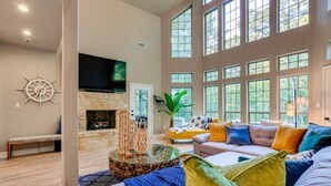 A spacious living room with a stone fireplace, large windows, and a comfortable seating area. - Charming 4-bedroom Lake house in Bonham with Pickleball/ Basketball court. (Bonham)