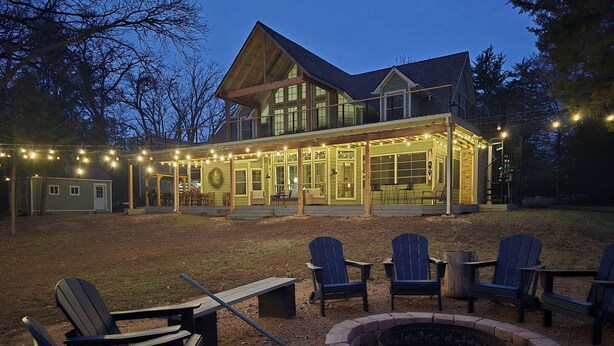 A large house with a covered patio area, outdoor seating, and a fire pit. - Charming 4-bedroom Lake house in Bonham with Pickleball/ Basketball court. (Bonham)