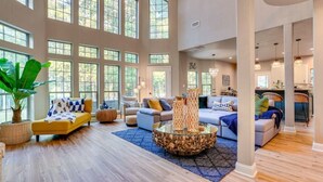 A spacious living room with large windows, a round coffee table, and multiple seating areas. - Charming 4-bedroom Lake house in Bonham with Pickleball/ Basketball court. (Bonham)