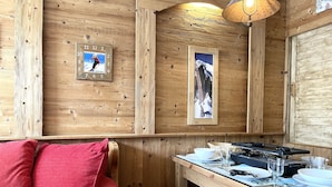 Ein Holzinterieur mit einem Esstisch, Stühlen und einem roten Kissen.
