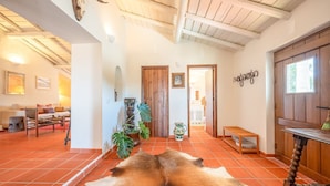 A spacious living area with a rustic decor, featuring a large wooden door, a dining table, and a sofa. - Authentic Alentejo Farmhouse (Arraiolos)