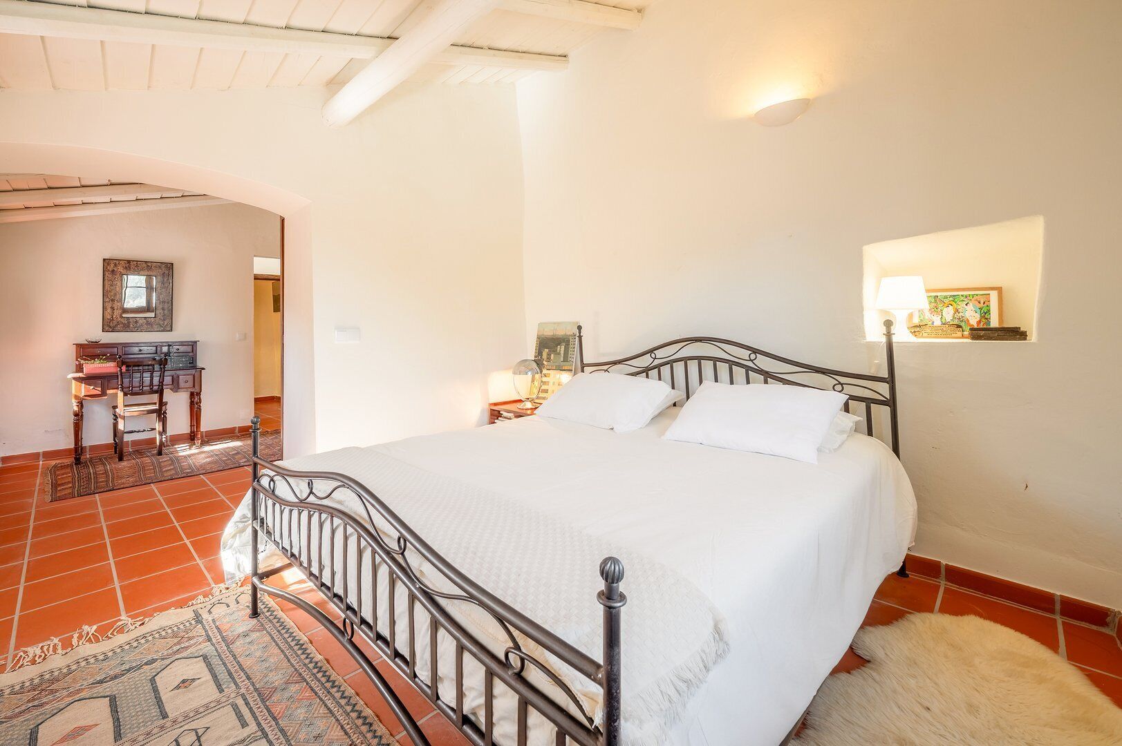 A bedroom with a bed, a desk, and a chair.