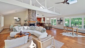 A spacious living room with a large sectional sofa, a wooden coffee table, and a dining area with a table and chairs. - Charming 3-bedroom Ranch in Weston Near Westport & Fairfield (Weston)