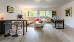Un salon moderne comprenant un coin repas, un canapé, une table basse et un téléviseur.