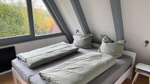 Une chambre avec deux lits, une fenêtre et un radiateur.