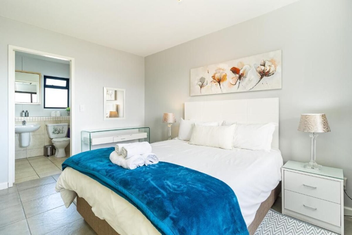 A hotel room with a bed, bedside table, and a bathroom visible through an open door.