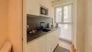 A compact kitchen with a microwave, sink, and a window providing natural light. - Foro Exclusive Suite - 5 mins from Duomo (Milano)