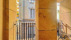 A narrow corridor with tiled walls and a metal gate leading to a balcony with a metal chair and a railing. - Foro Exclusive Suite - 5 mins from Duomo (Milano)