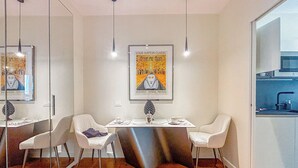 A modern dining area with a glass partition, white chairs, a table with a vase, and a poster on the wall. - Foro Exclusive Suite - 5 mins from Duomo (Milano)