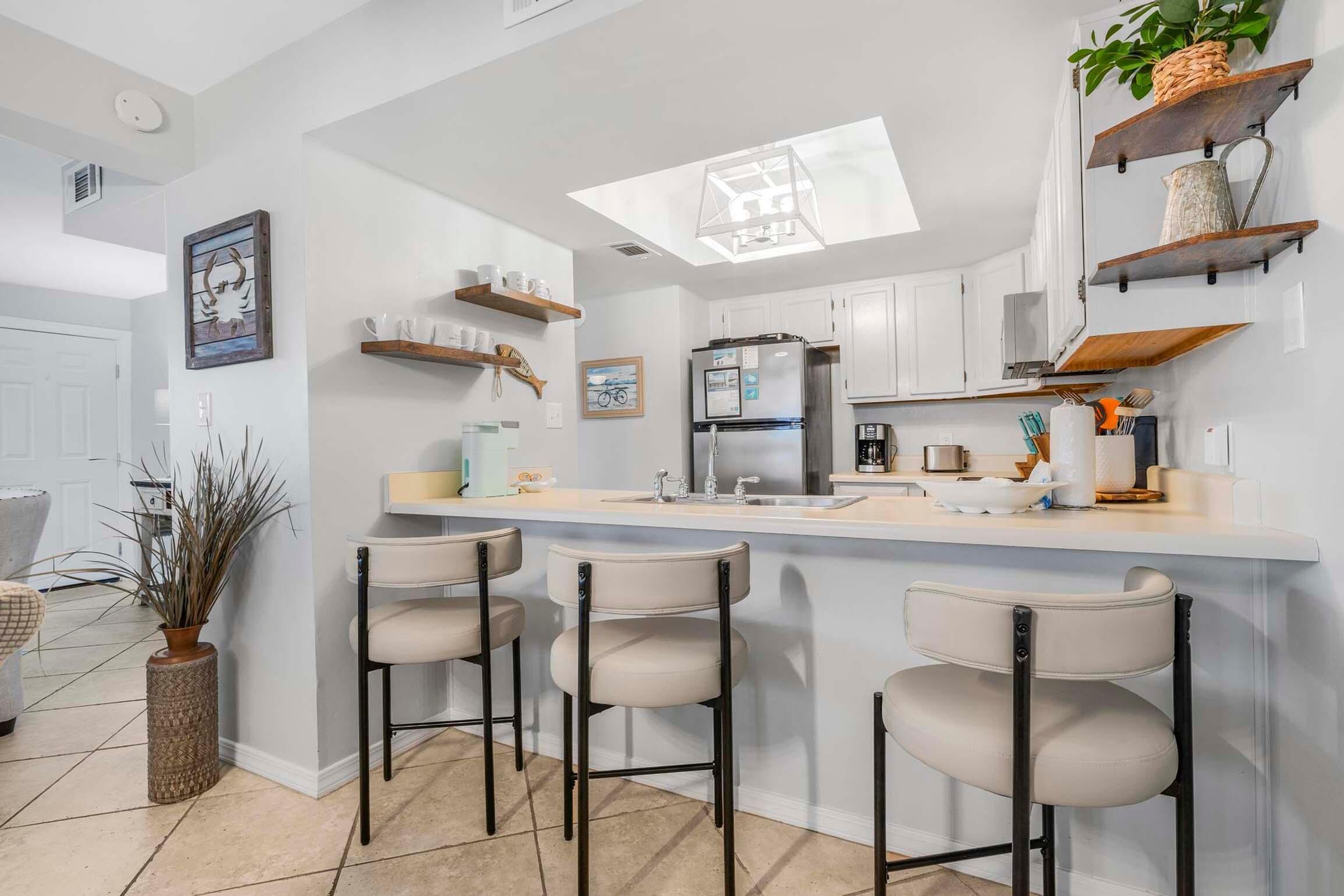 A modern kitchen with a central island, bar stools, and built-in shelves.