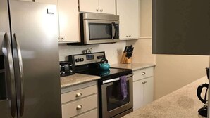 A modern kitchen with stainless steel appliances, a microwave, oven, and a kettle on the countertop. - Spacious Family Home with Fenced Yard (Modesto)
