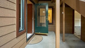 A wooden exterior with a green door, a window, and a doormat. - Convenient Townhome Near Downtown McCall (McCall)