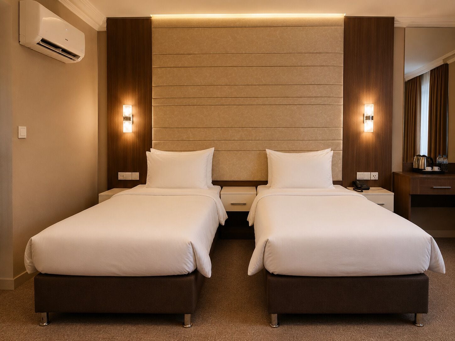 A hotel room with two beds, a wooden headboard, bedside lamps, a desk with a phone, and a mirror.
