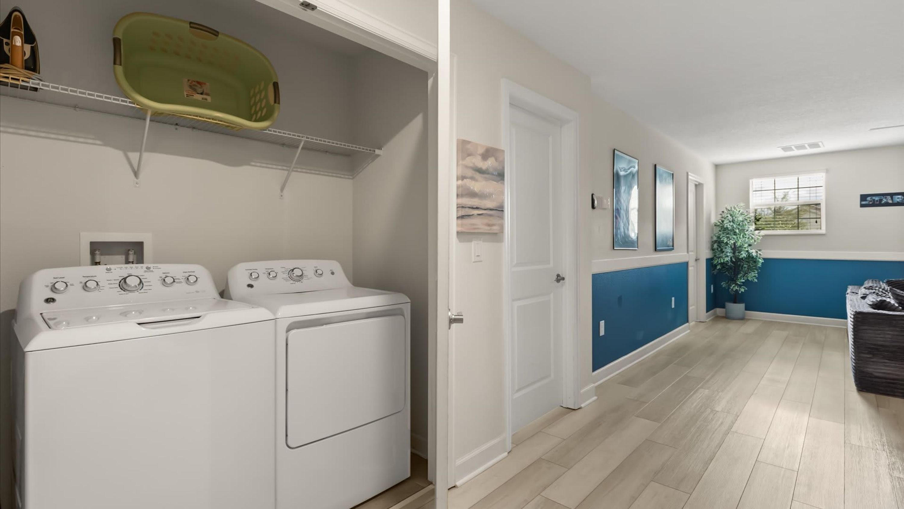 A laundry room with two washing machines and a drying rack.