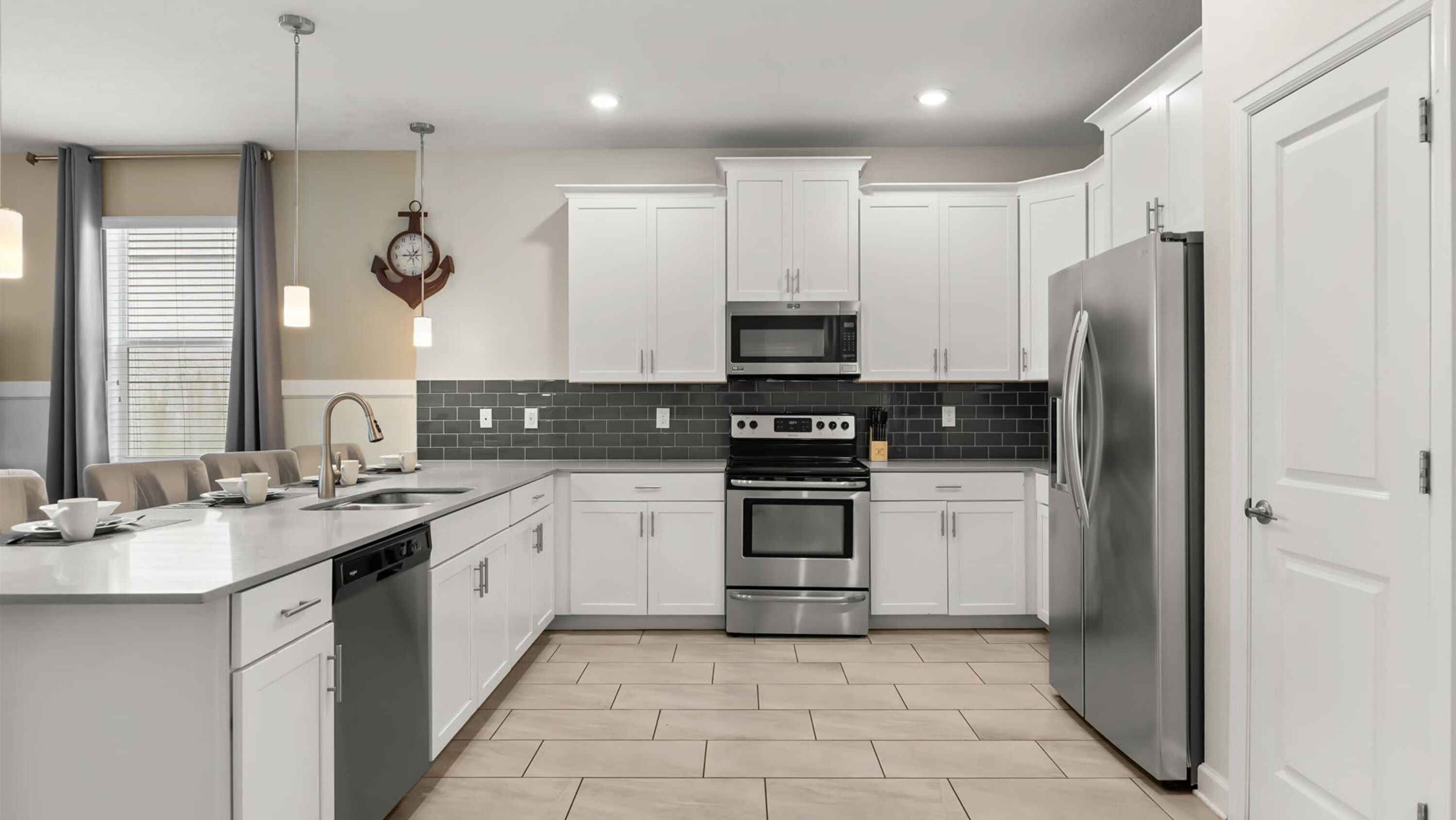 A modern kitchen with white cabinets, a stainless steel refrigerator, a built-in oven, and a microwave.