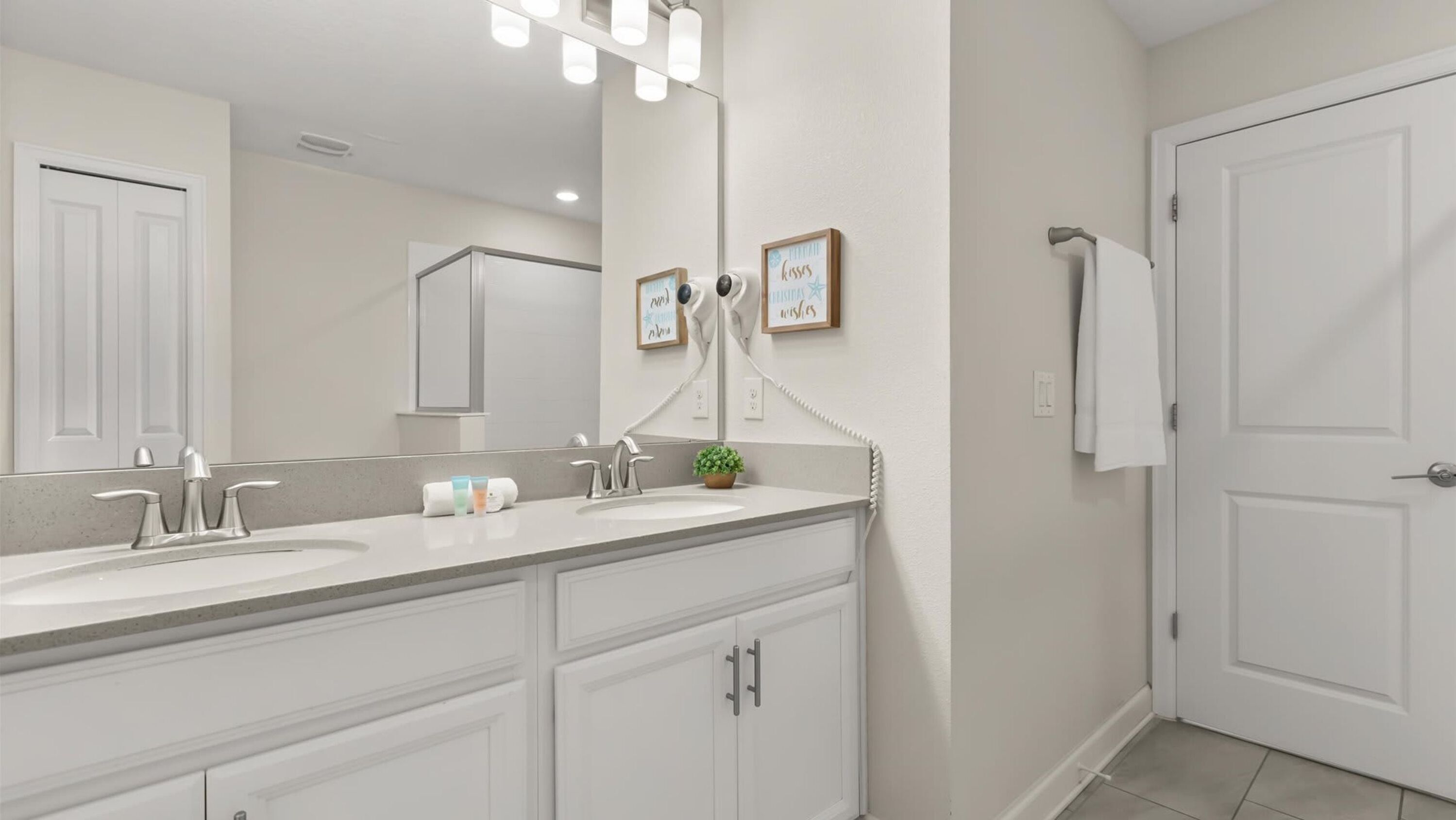 Une salle de bain moderne avec deux lavabos, un grand miroir et un porte-serviettes.