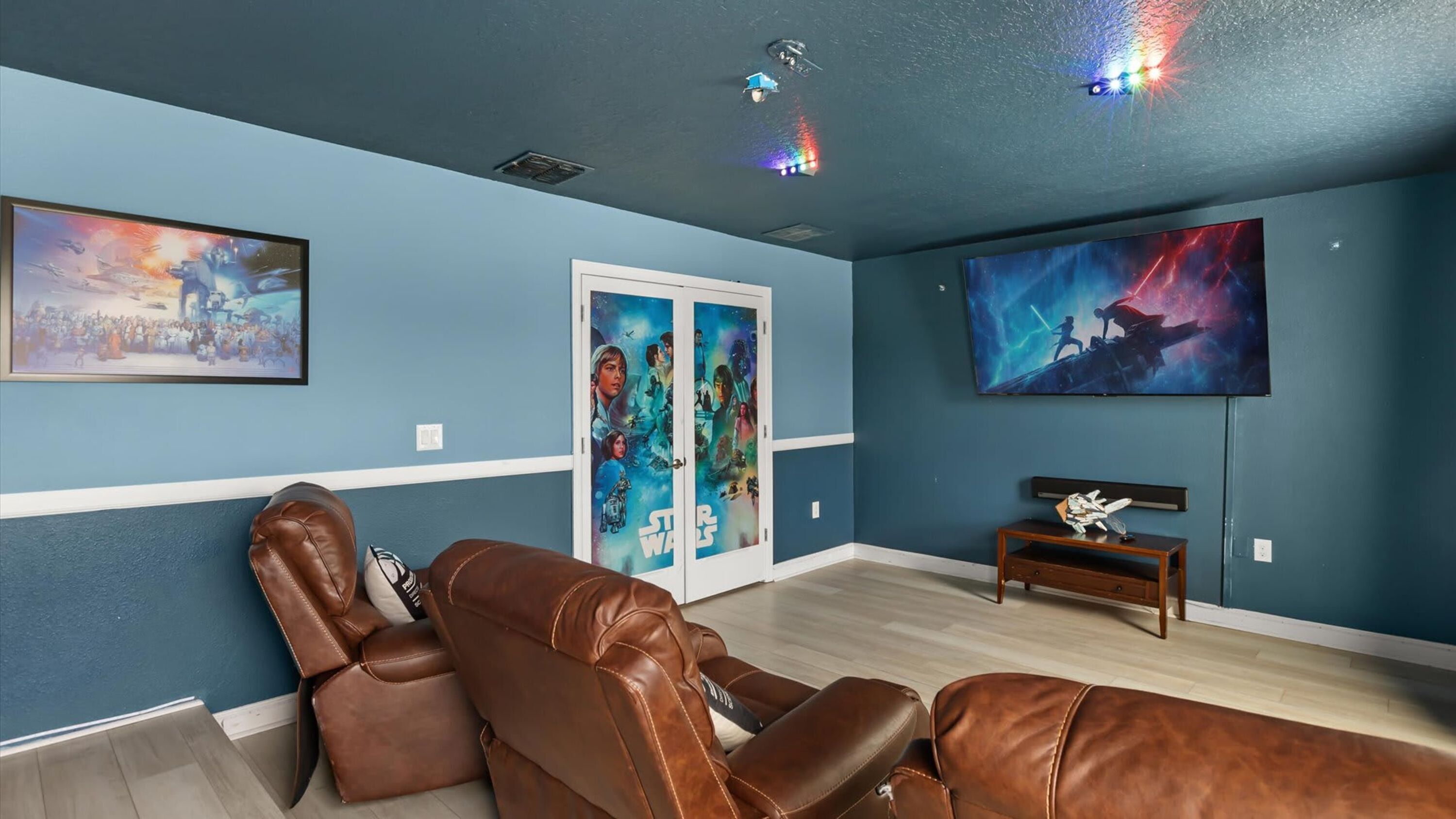Une salle de cinéma maison équipée d’un fauteuil en cuir inclinable, d’un téléviseur à écran plat et d’une décoration sur le thème de Star Wars.