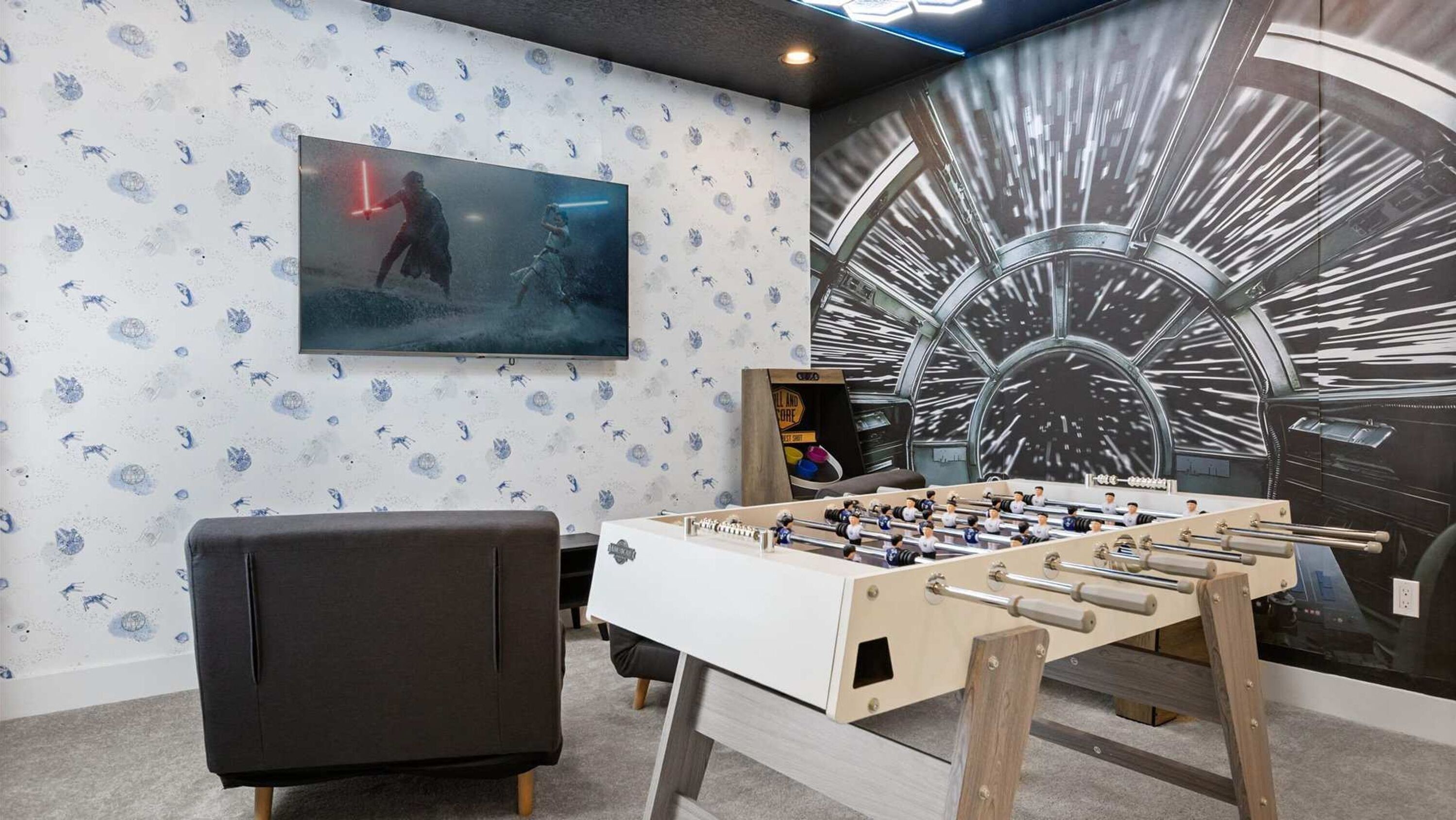 A room with a foosball table, a large wall mural, and a seating area.