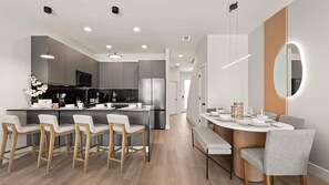 Een moderne keuken met een centraal kookeiland, een bar met zitplaatsen, en een eethoek met een ronde tafel en stoelen.