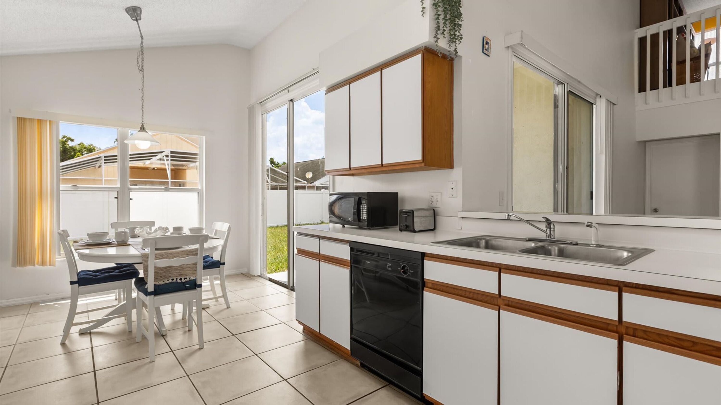 A modern kitchen with white cabinets, a black microwave, and a dishwasher.