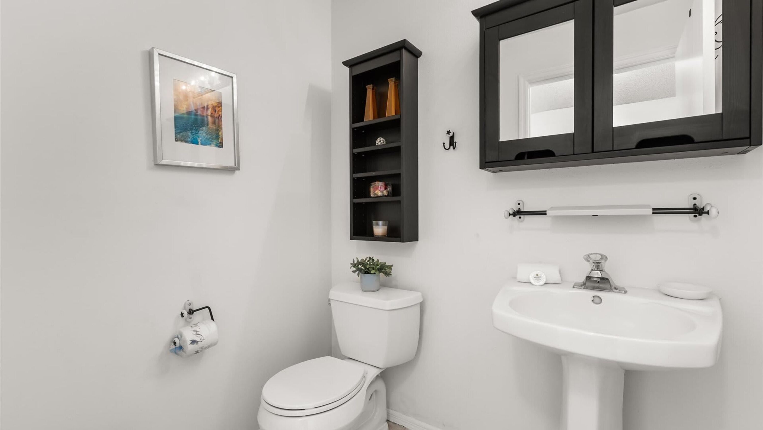Ein modernes Badezimmer mit Toilette, Waschbecken und Ablage für Pflegeprodukte.
