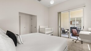 A modern hotel room with a large bed, a desk, a chair, and a sliding glass door leading to a balcony. - Upstay 3BR Family-friendly Stylish Retreat w Patio (Kissimmee)