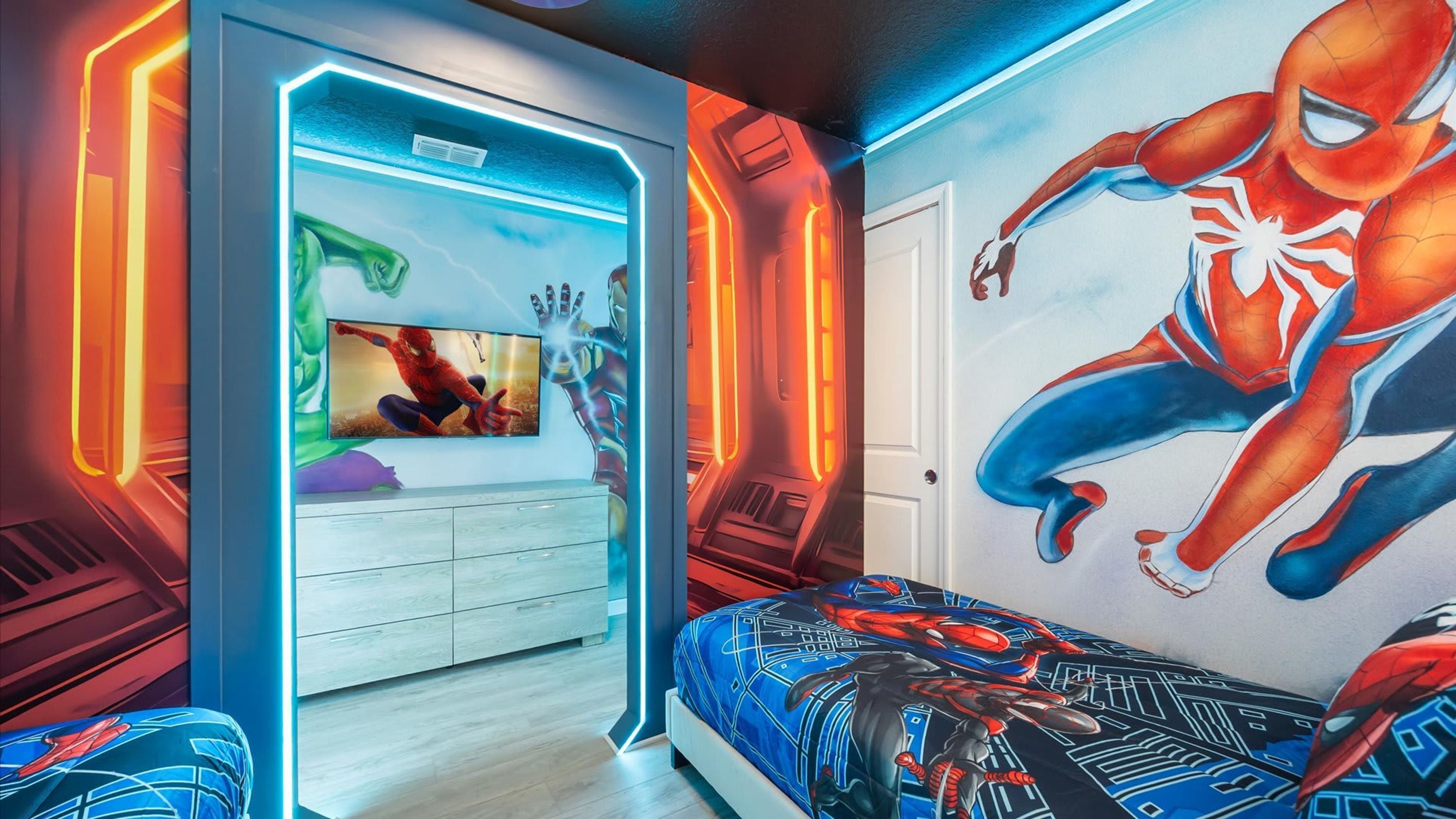 A bedroom with a large Spider-Man mural, a TV, and a modern dresser.