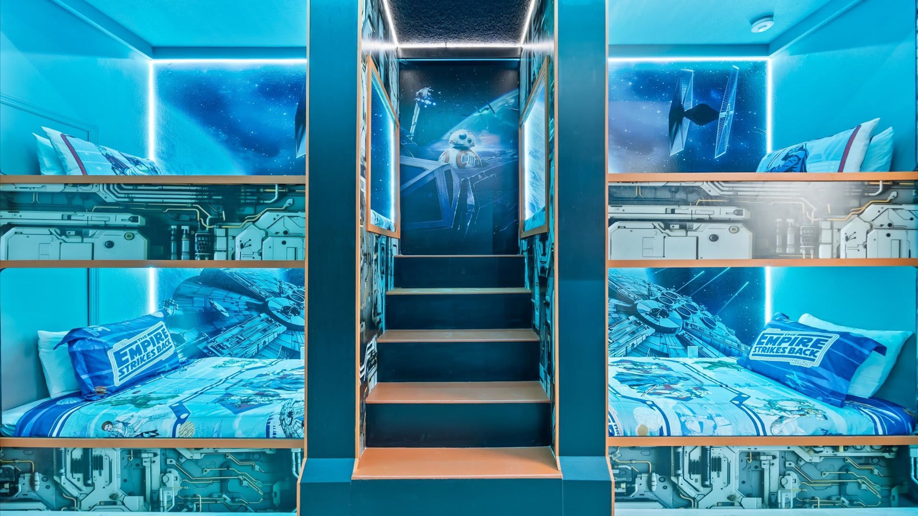 A room with bunk beds, each bed featuring a space-themed design.