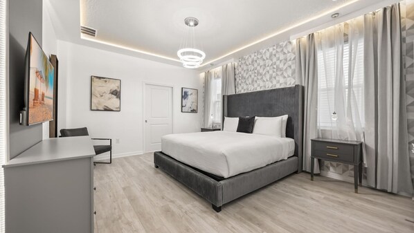 A modern bedroom with a large bed, bedside tables, a desk, and a TV. - Newly Renovated Home w Pool Hot Tub Games Room (Davenport)
