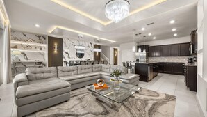 Een moderne woonkamer met een hoekbank, een glazen salontafel en een vloerkleed met een marmerpatroon.
