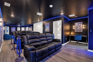 Una habitación moderna con un sofá de cuero negro, un escritorio y una silla de oficina azul.