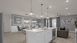 A modern kitchen with a central island, pendant lighting, and a ceiling fan. - Upstay 10br Family Retreat w Pool Hot Tub Games (Clermont)