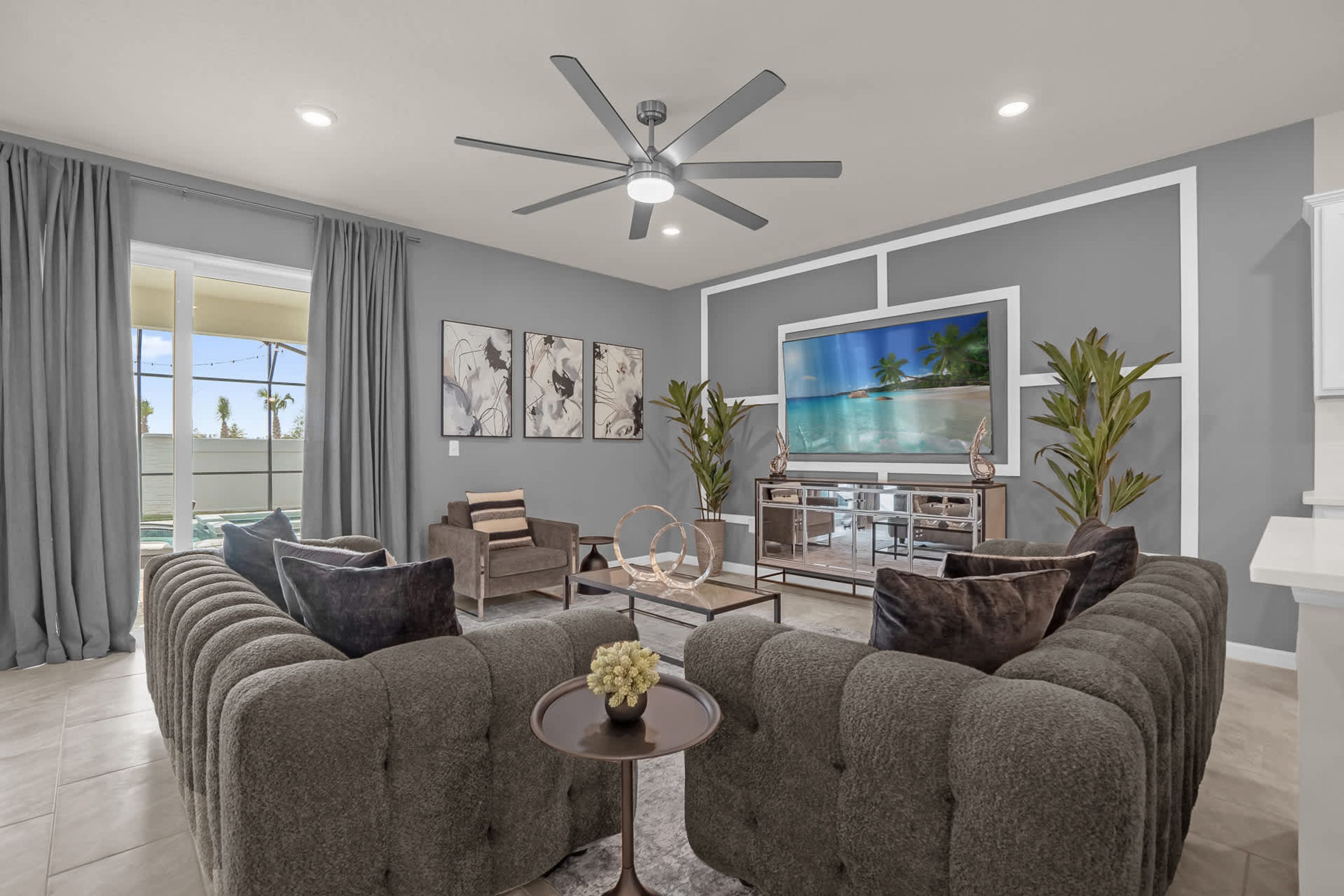 A modern living room with a grey sofa set, a coffee table, and a flat-screen TV mounted on the wall.