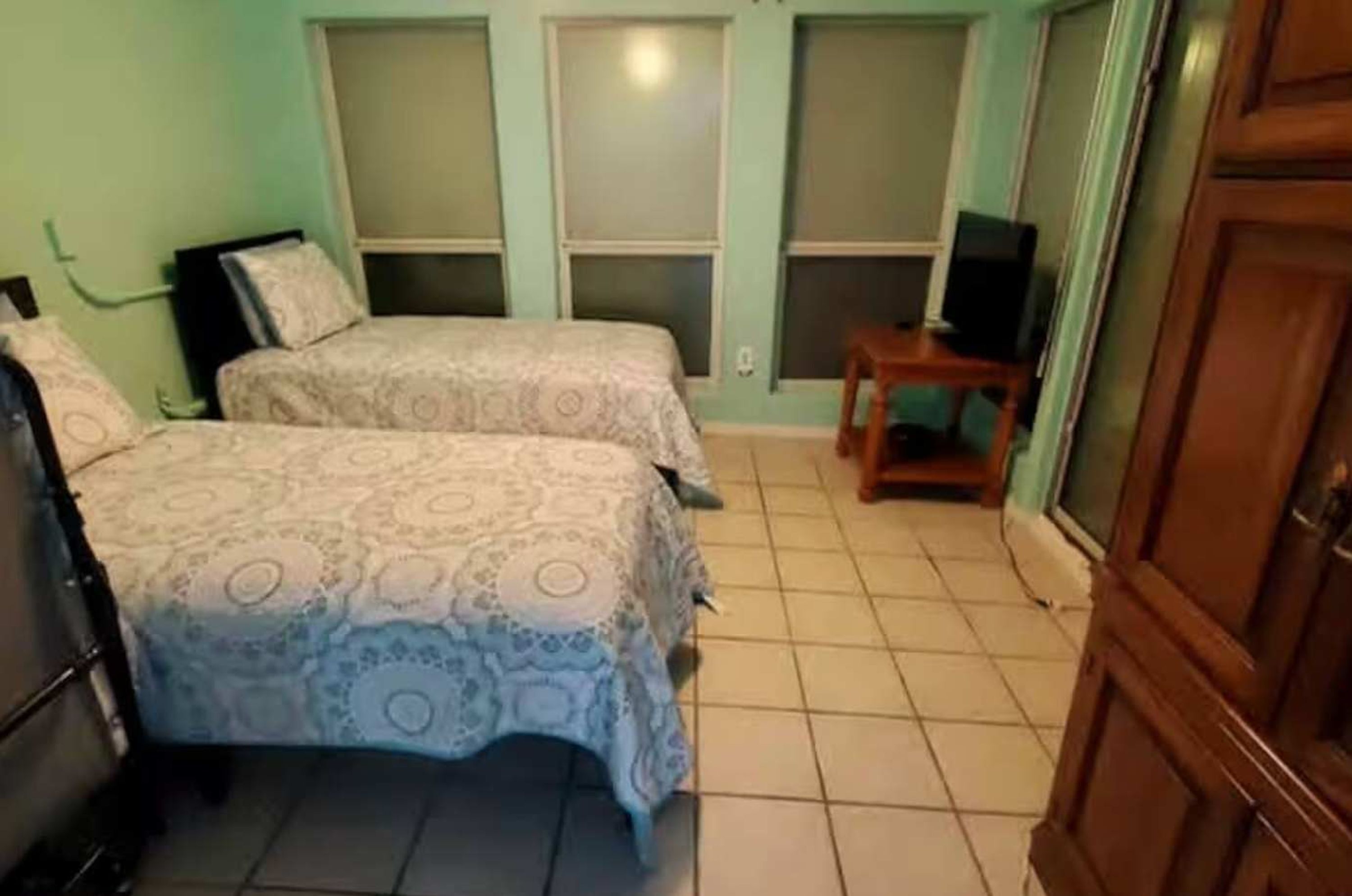 A small, clean room with two beds, a television, and a wooden wardrobe.
