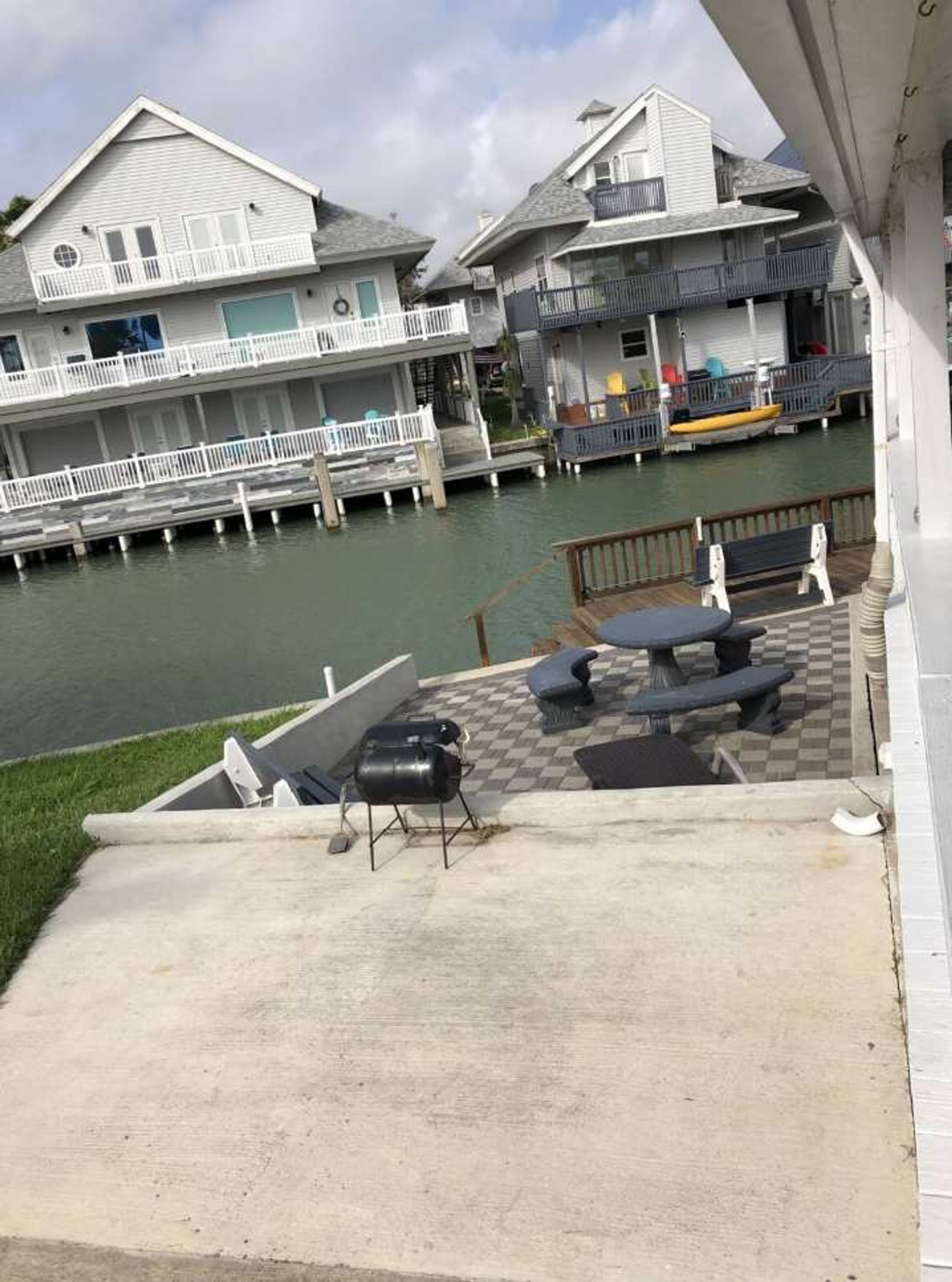 Een pand aan het water met een overdekt terras, zitplaatsen buiten en uitzicht op de aangrenzende huizen.