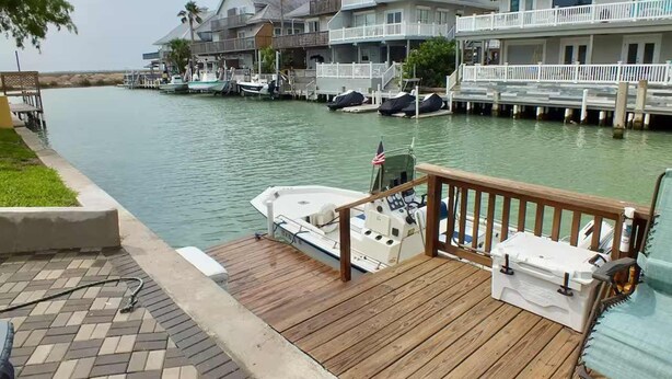 Ein Ufergrundstück mit Steg, einem Boot und einer Holzterrasse.