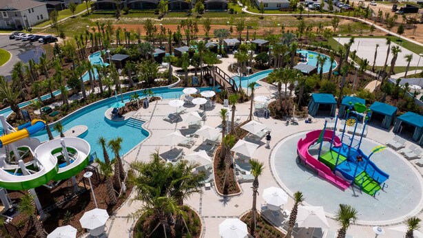 A large outdoor swimming pool area with multiple water slides and lounge chairs. - Upstay Family Fun 5BR Retreat w Pool Games Room (Clermont)