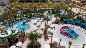 Un amplio espacio de piscina al aire libre con múltiples toboganes y sillas de descanso.