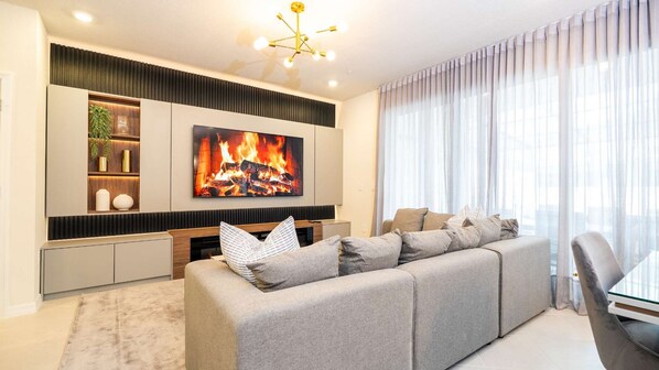 Una sala de estar moderna con un televisor de pantalla plana grande, un sofá y un comedor.