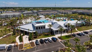 A residential complex with a central swimming pool, multiple parking spaces, and a well-maintained landscape with palm trees. - Upstay Family Fun 5BR Retreat w Pool Games Room (Clermont)
