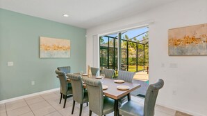 A dining area with a table set for six, six chairs, and two paintings on the walls. - Resort Home w Pool Games BBQ - Near Disney (Kissimmee)