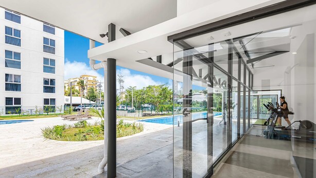 A modern hotel lobby with a glass wall offering a view of a pool and outdoor area. - Contemporary Viva Jaco Residences Suite With Pool (Jacó)