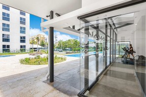 A modern hotel lobby with a glass wall offering a view of a pool and outdoor area. - Contemporary Viva Jaco Residences Suite With Pool (Jacó)