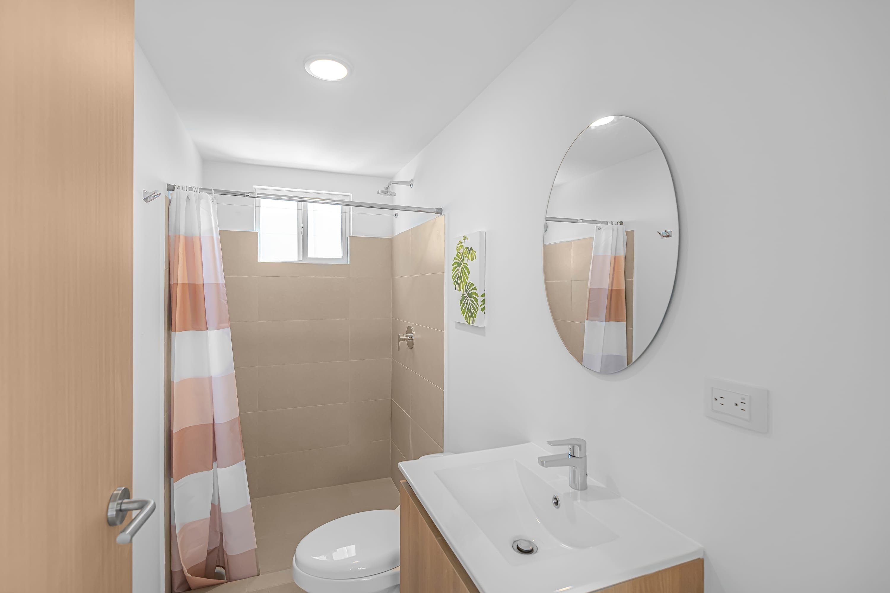 A modern bathroom with a shower, toilet, and sink.