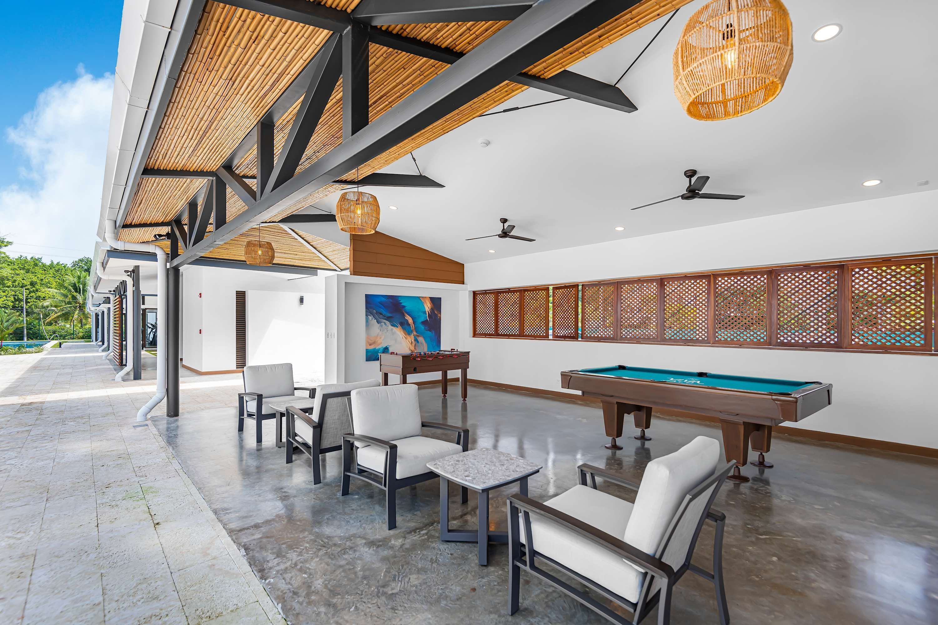 Un espace piscine comprenant une table de billard, des chaises et un grand tableau accroché au mur.