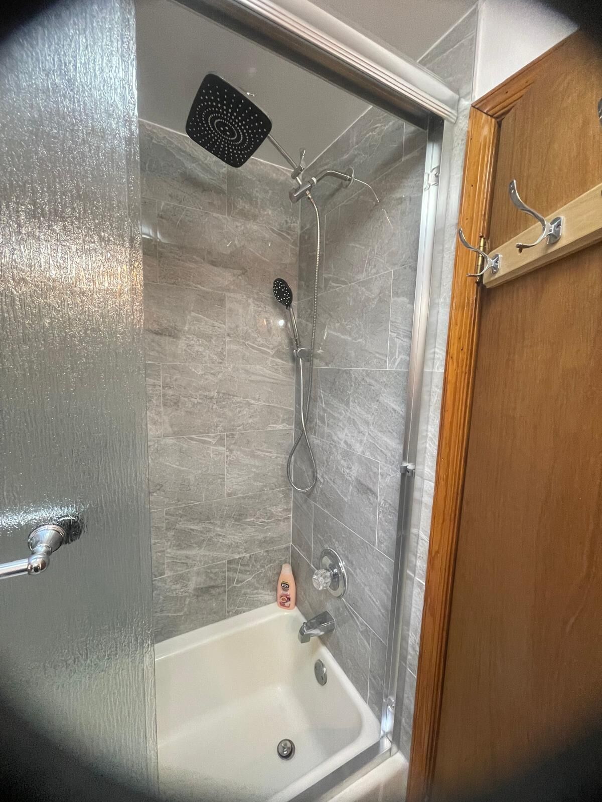 A shower enclosure with a handheld showerhead, a handheld showerhead, and a handheld showerhead.